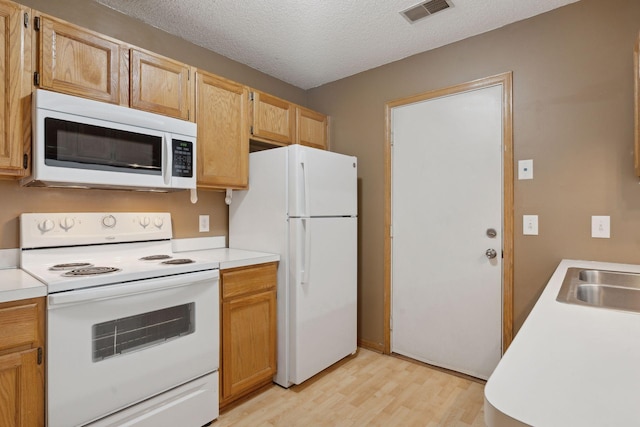 kitchen featuring sink, a textured ceiling, white appliances, and light hardwood / wood-style floors