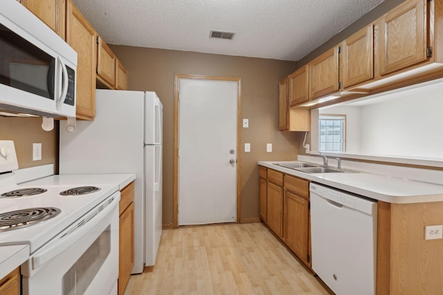 kitchen with white appliances, light hardwood / wood-style floors, sink, and a textured ceiling