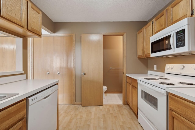 kitchen featuring white appliances, light hardwood / wood-style flooring, and a textured ceiling