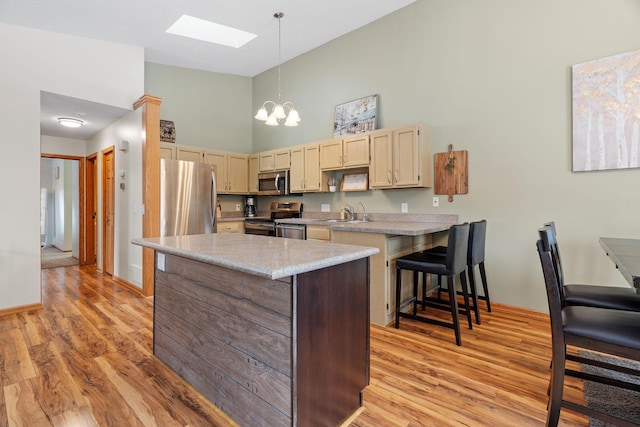 kitchen featuring stainless steel appliances, light countertops, decorative light fixtures, and light wood-style floors