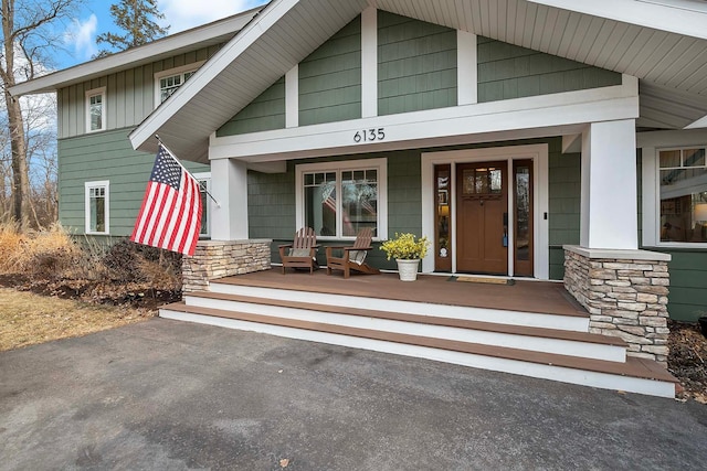 property entrance featuring stone siding, a porch, and board and batten siding