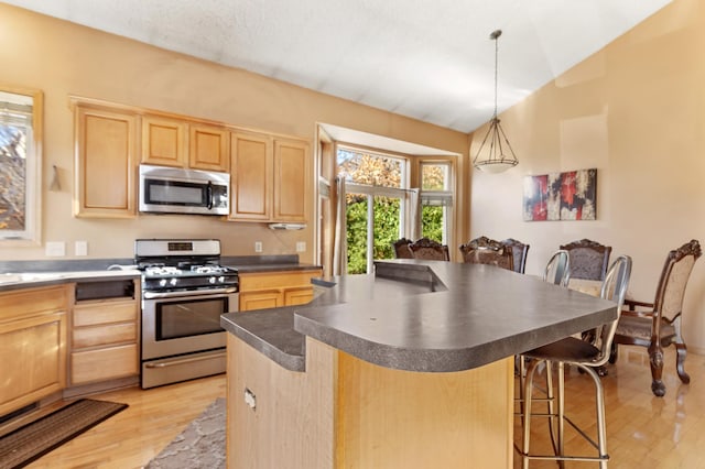 kitchen with a kitchen island, appliances with stainless steel finishes, pendant lighting, and light brown cabinets