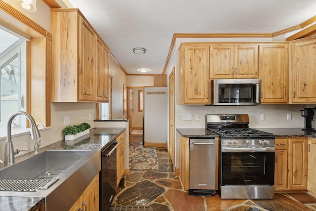 kitchen featuring ornamental molding, appliances with stainless steel finishes, sink, and dark stone counters