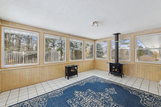 unfurnished sunroom with a healthy amount of sunlight and a wood stove