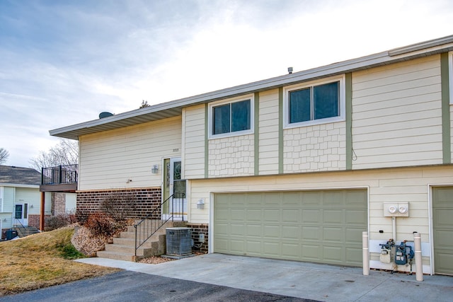 view of front of property with concrete driveway, central AC unit, and a garage