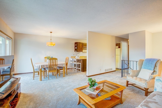 living room with light colored carpet, baseboards, visible vents, and a textured ceiling