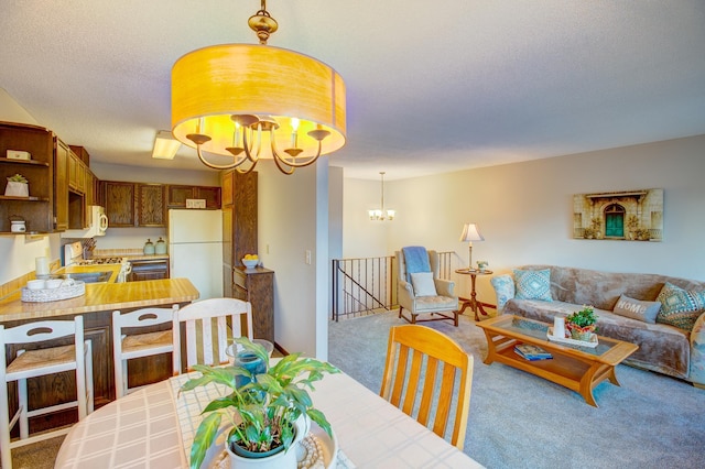 carpeted dining room with an inviting chandelier and a textured ceiling