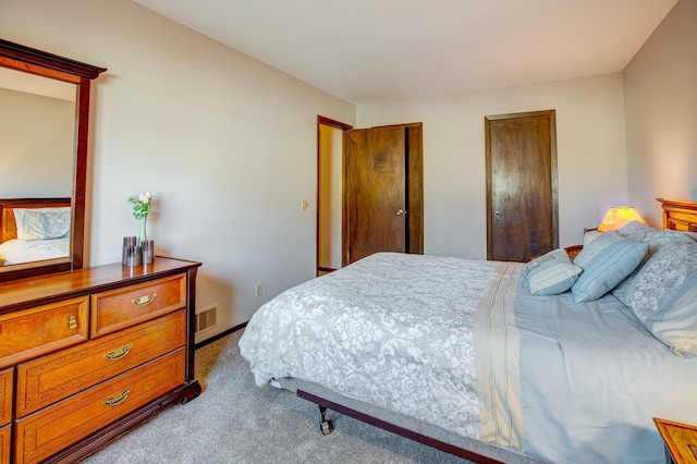 bedroom featuring carpet, visible vents, and two closets