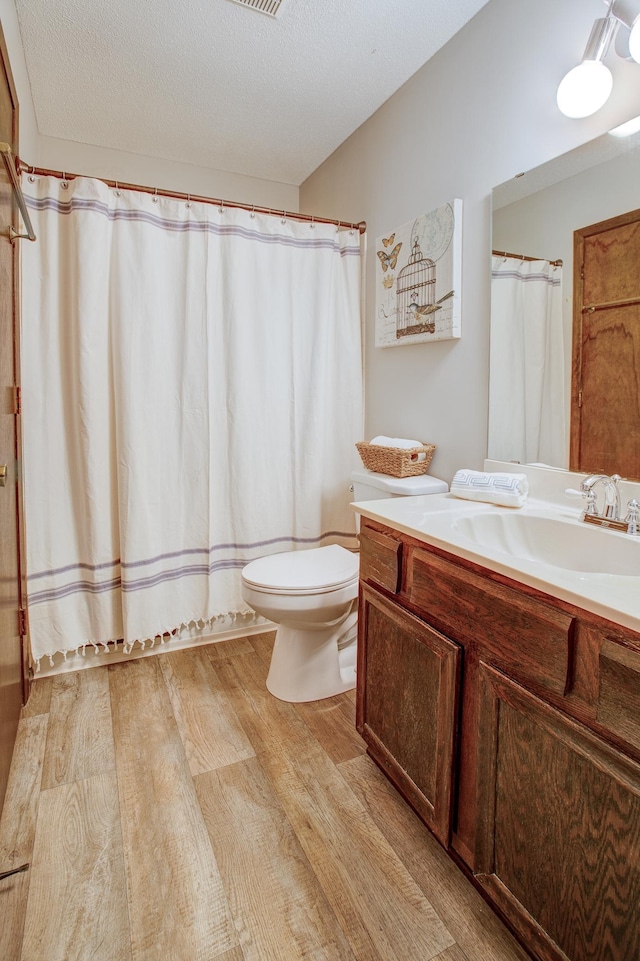 full bath featuring vanity, toilet, wood finished floors, and a textured ceiling