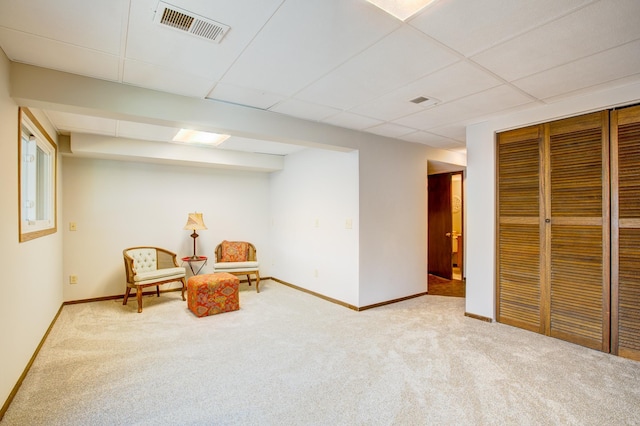 living area with a drop ceiling, baseboards, visible vents, and carpet floors