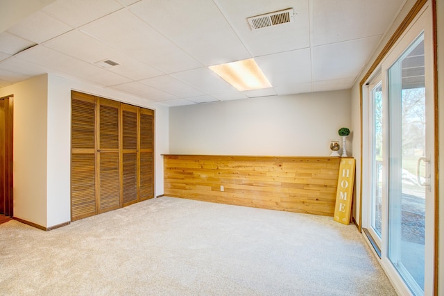 empty room featuring a drop ceiling, visible vents, and carpet floors