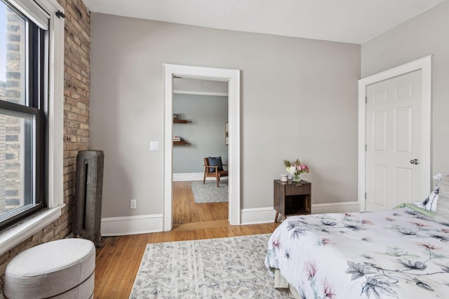 bedroom featuring radiator, light hardwood / wood-style floors, and multiple windows