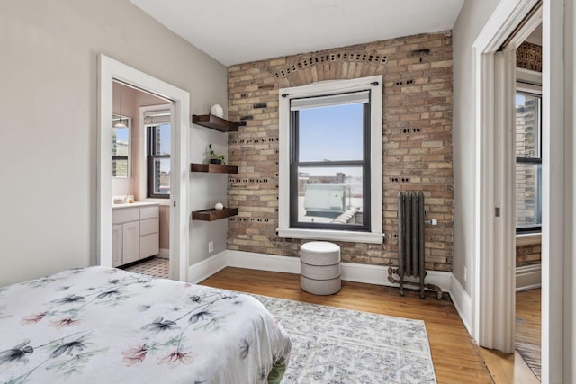 bedroom featuring radiator heating unit, light hardwood / wood-style floors, and ensuite bathroom