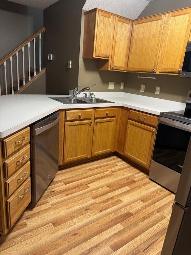 kitchen featuring sink, light hardwood / wood-style flooring, stainless steel appliances, and a textured ceiling