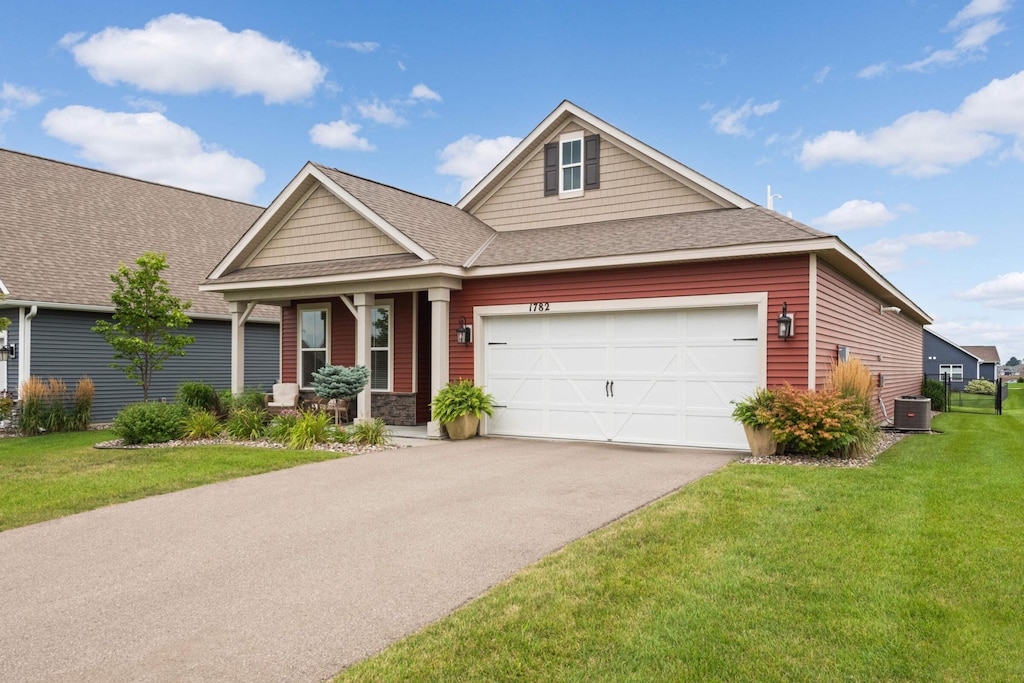 craftsman-style home featuring a garage, a front yard, and central air condition unit