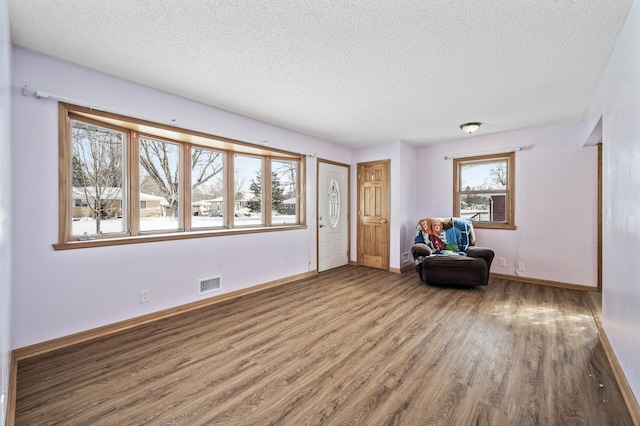 unfurnished room with visible vents, a textured ceiling, baseboards, and wood finished floors