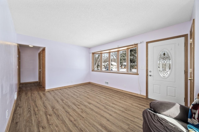 entrance foyer featuring visible vents, baseboards, a textured ceiling, and wood finished floors