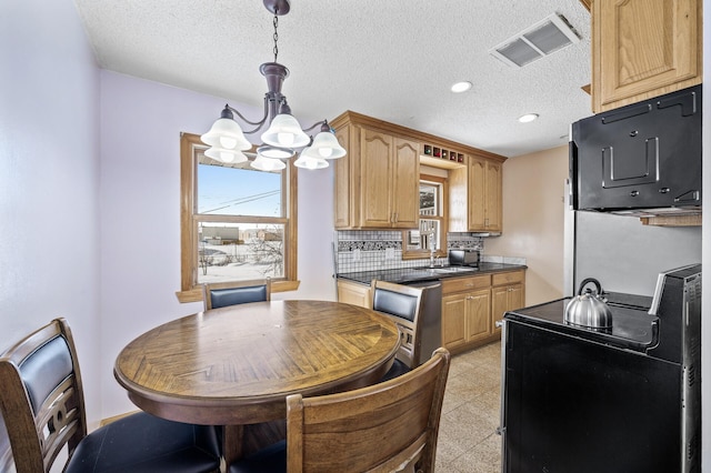 kitchen featuring a wealth of natural light, visible vents, dark countertops, and electric range