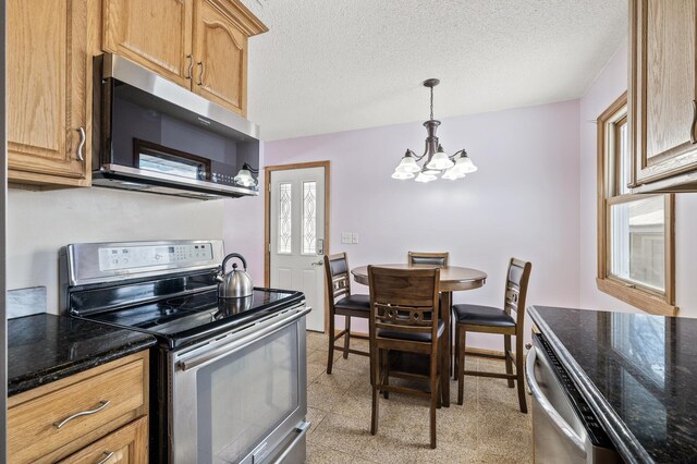 kitchen featuring dark stone counters, a textured ceiling, stainless steel appliances, and an inviting chandelier