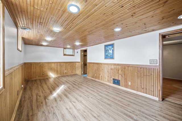 below grade area with a wainscoted wall, wood walls, wooden ceiling, and visible vents