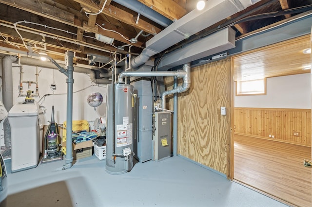 basement featuring heating unit, wooden walls, and water heater