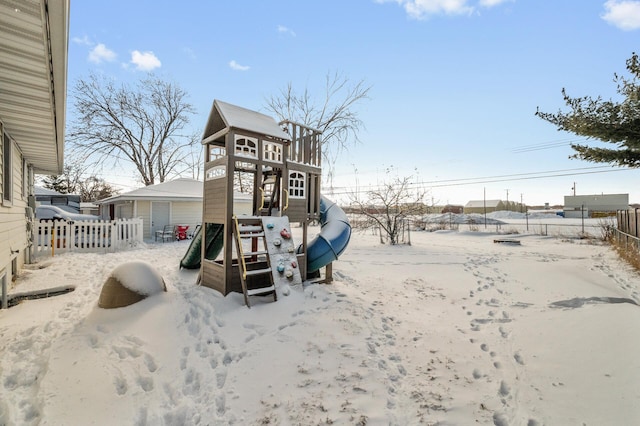 snow covered playground with fence and a playground