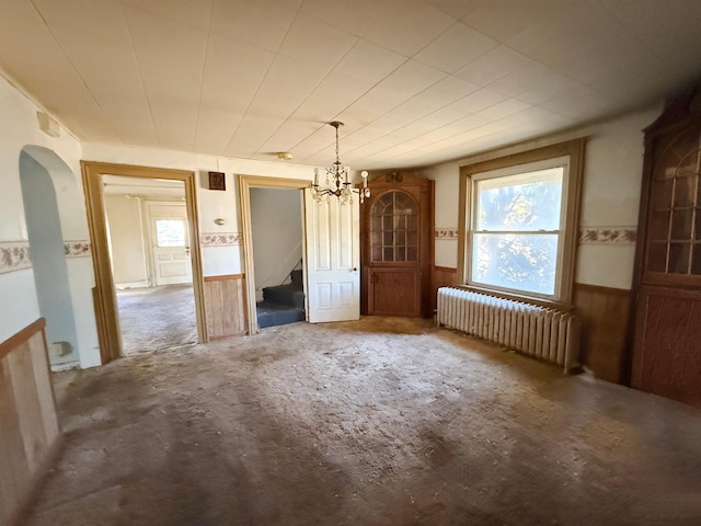 interior space with radiator, a notable chandelier, and wooden walls