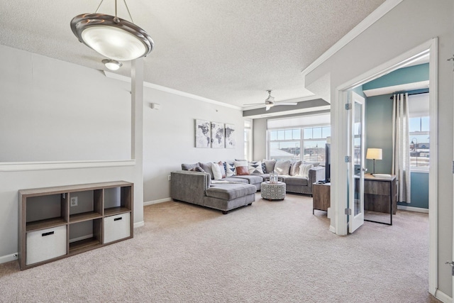 living area with a textured ceiling, ornamental molding, a ceiling fan, and light colored carpet