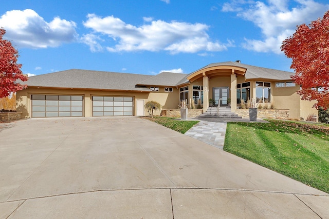 view of front of house featuring a garage, french doors, and a front lawn