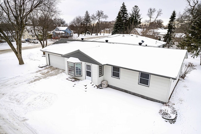 snow covered rear of property featuring a garage