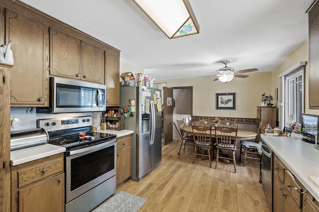 kitchen with ceiling fan, stainless steel appliances, and light wood-type flooring