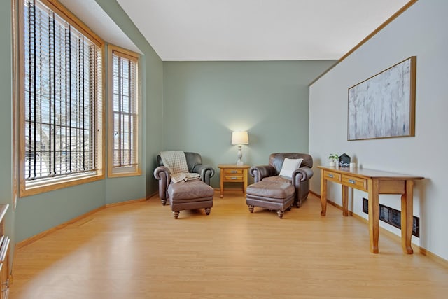 living area featuring a wealth of natural light, light hardwood / wood-style floors, and vaulted ceiling