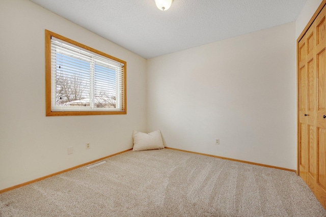 unfurnished bedroom with carpet, a textured ceiling, and a closet