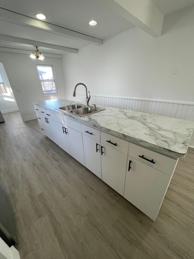 kitchen with sink, beamed ceiling, light hardwood / wood-style floors, and white cabinets