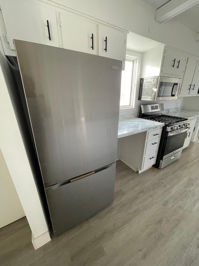 kitchen with white cabinetry, stainless steel appliances, and light hardwood / wood-style floors