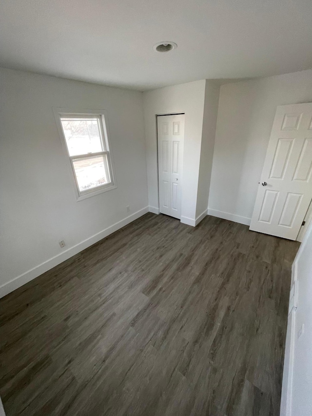 unfurnished bedroom featuring dark wood-type flooring and a closet