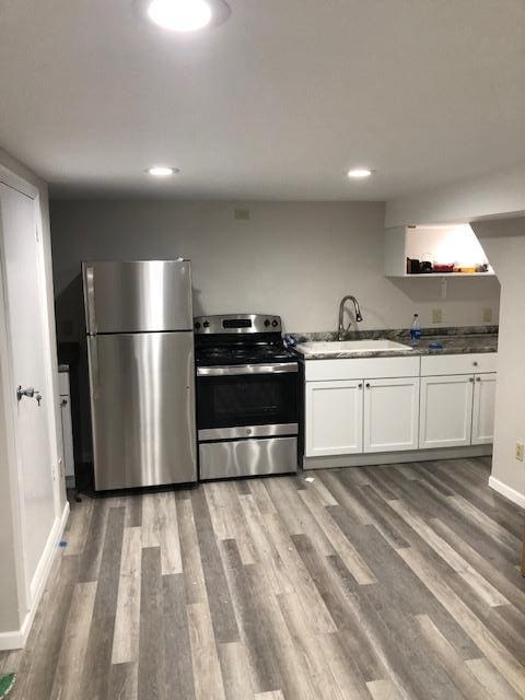 kitchen featuring appliances with stainless steel finishes, sink, wood-type flooring, and white cabinets