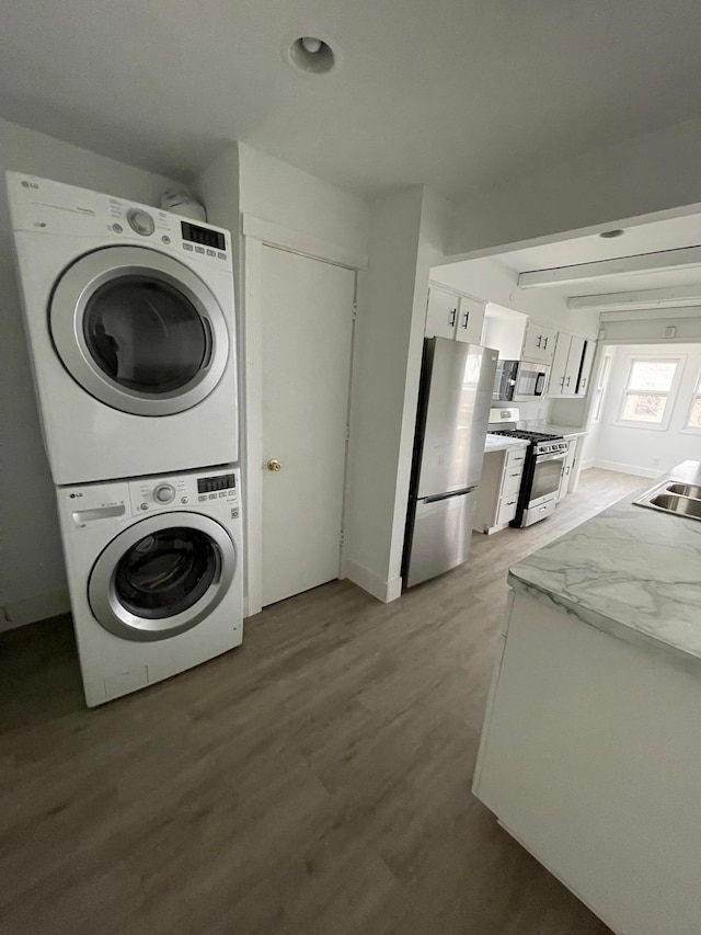 laundry room with stacked washer and clothes dryer and wood-type flooring