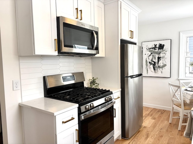 kitchen featuring light hardwood / wood-style flooring, white cabinetry, stainless steel appliances, light stone counters, and tasteful backsplash