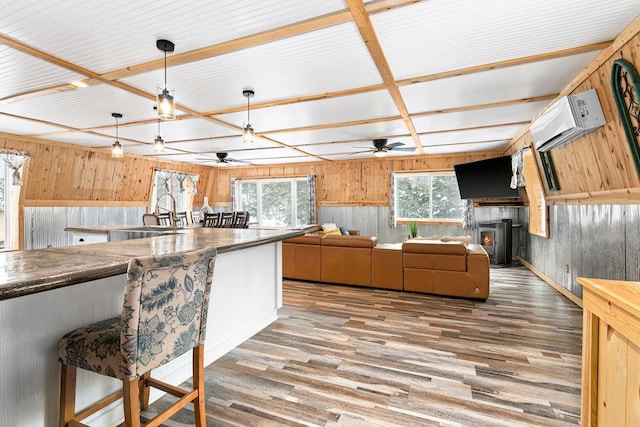 kitchen with sink, hardwood / wood-style flooring, wooden walls, a wall mounted air conditioner, and decorative light fixtures