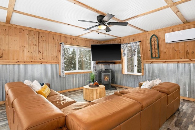 living room with an AC wall unit, wood-type flooring, a wood stove, and a wealth of natural light