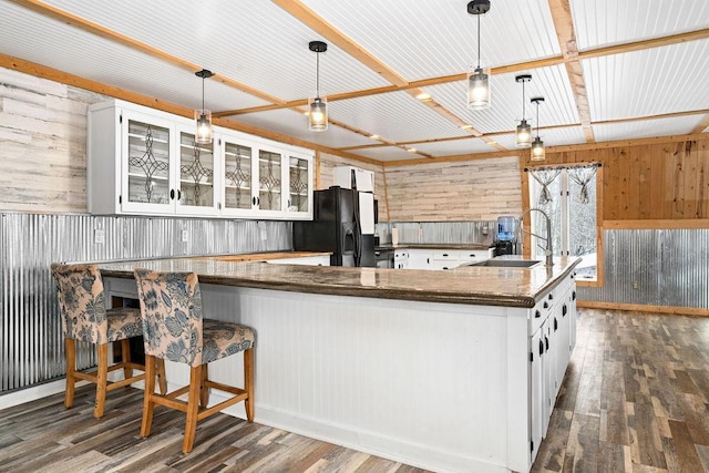 kitchen with decorative light fixtures, white cabinets, dark hardwood / wood-style flooring, kitchen peninsula, and black fridge