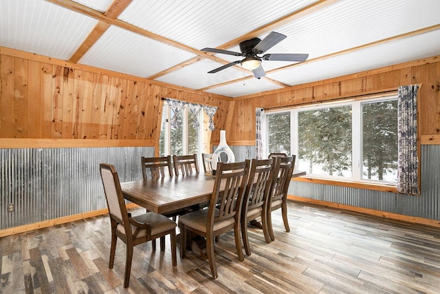 dining area featuring hardwood / wood-style floors, wooden walls, and ceiling fan