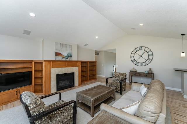 living room with visible vents, baseboards, light wood-style flooring, vaulted ceiling, and a fireplace