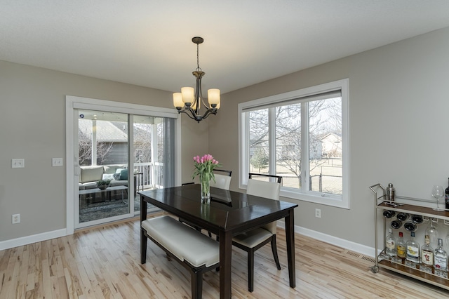 dining room with a chandelier, light wood finished floors, and baseboards