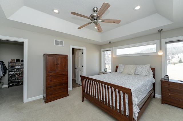 bedroom featuring baseboards, visible vents, a raised ceiling, a walk in closet, and recessed lighting