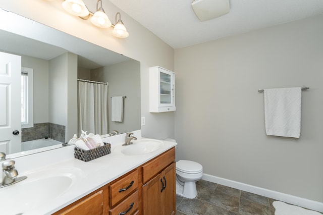 full bathroom with double vanity, a sink, toilet, and baseboards