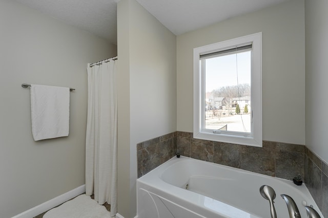 full bathroom featuring baseboards and a bath