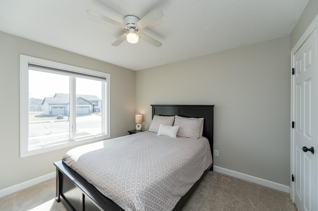 bedroom featuring a ceiling fan, light carpet, and baseboards