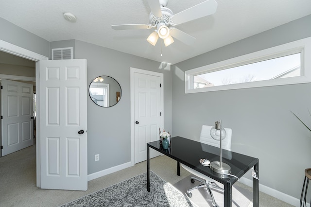 office space featuring carpet, baseboards, visible vents, and a ceiling fan